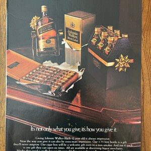 May include: A vintage advertisement for Johnnie Walker Black Label Scotch Whisky. The ad features a bottle of Johnnie Walker Black Label Scotch Whisky, a box of cigars, and a six-pack of Johnnie Walker Black Label Scotch Whisky. The ad text reads "Its not only what you give, its how you give it." and "Giving Johnnie Walker Black 12 year old is always impressive."