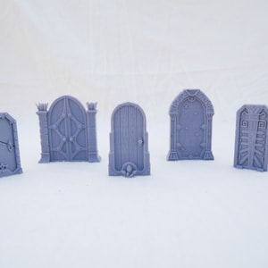 May include: Six different miniature doors made of gray plastic. The doors are all different styles, with some having intricate details and others being more simple.