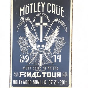Puede incluir: Un letrero de metal blanco y negro con el texto "Motley Crue" en blanco. El letrero presenta una calavera con alas, guadañas cruzadas y el texto "All Bad Things Must Come To An End - The Final Tour - Hollywood Bowl LA 07-21-2014".