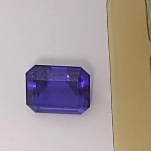 K&ouml;nnte beinhalten: Ein tiefvioletter Edelstein mit einem rechteckigen Smaragdschliff.