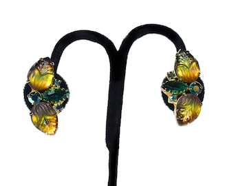 May include: A pair of gold tone earrings with carved amber leaves and green and blue rhinestones.