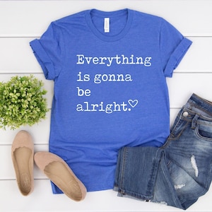 May include: A royal blue t-shirt with the text "Everything is gonna be alright." in white with a small heart symbol.