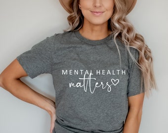 Könnte beinhalten: Ein graues T-Shirt mit dem Text "Mental Health matters" in weißen Buchstaben mit einem kleinen Herzsymbol.