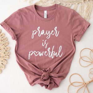 May include: A mauve colored t-shirt with the text "prayer is powerful" in white lettering with a small heart replacing the "o" in powerful.