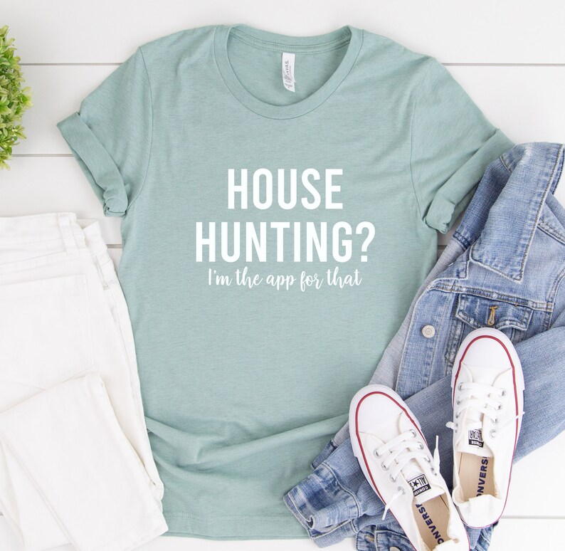 May include: A light blue t-shirt with the text "HOUSE HUNTING? I'm the app for that" in white.