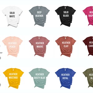 May include: Twelve t-shirt color options displayed on a white background. The colors include solid white, deep heather, solid black, heather raspberry, heather peach, heather mauve, heather clay, heather cardinal, heather mustard, heather dusty blue, heather royal, and heather olive.