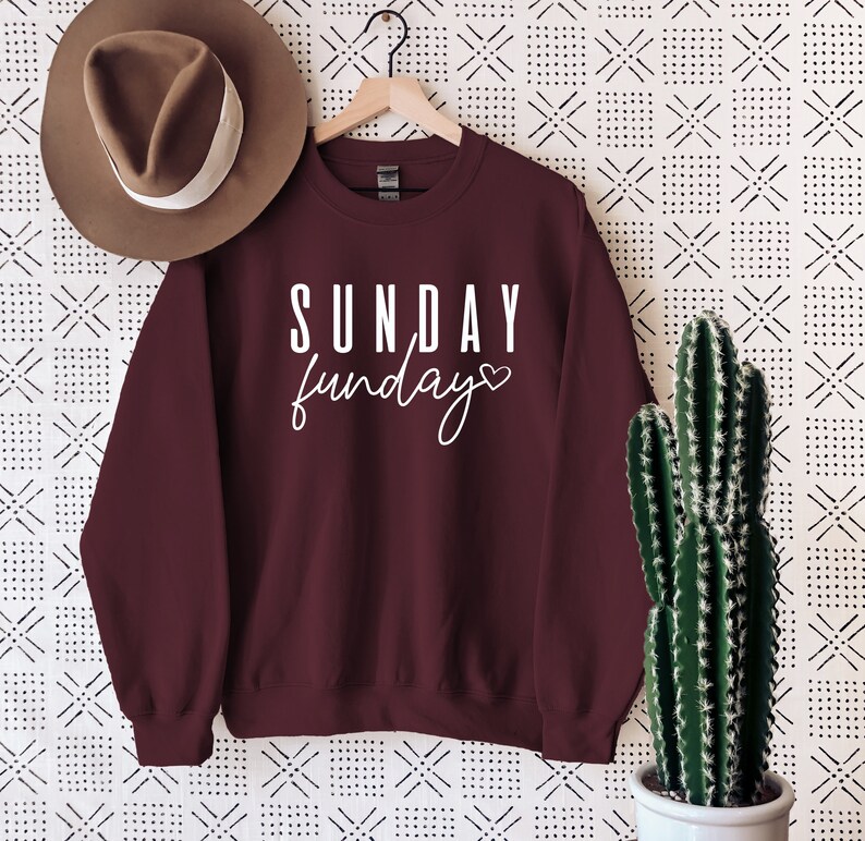 May include: Burgundy sweatshirt with white text that reads "SUNDAY funday" with a small heart symbol.