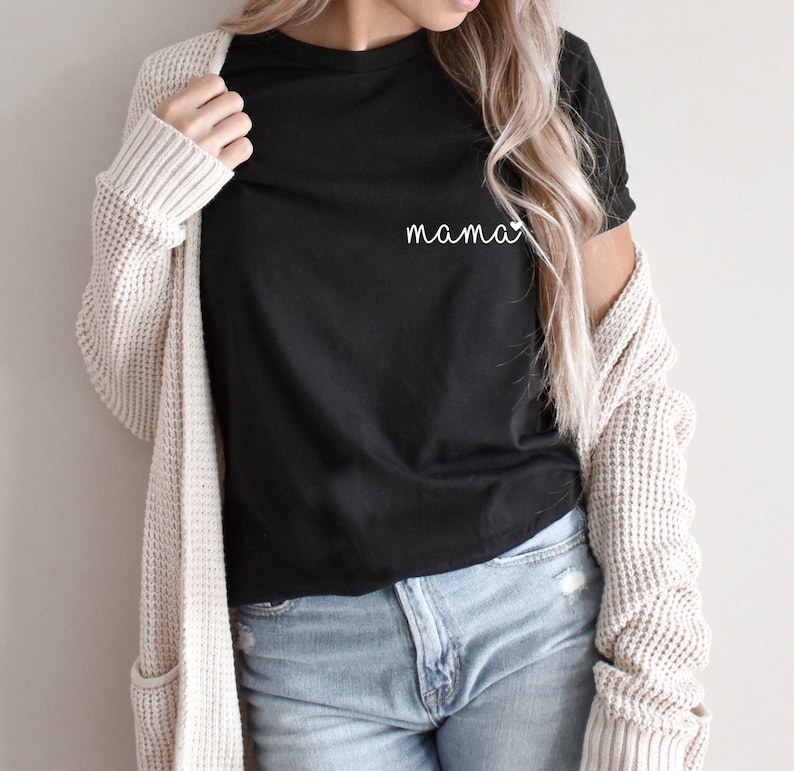 A black t-shirt with the word "mama" written in white script with a small heart next to it. The shirt is being worn with a trendy mom jeans and a beige cardigan. Mama Pocket Design TShirt Minimalist Mom Gift Cute Boy Mom Shirt Trendy Girl Mama Apparel Mothers Day Gift Bella Canvas Shirt