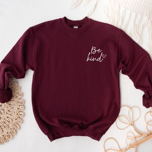 May include: Burgundy sweatshirt with the text "Be kind" in white lettering with a small heart.
