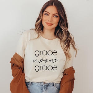 May include: A white t-shirt with the text "grace upon grace" in black lettering with a small heart symbol.