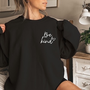 May include: Black sweatshirt with a white graphic that says "Be kind" with a small heart symbol.