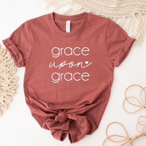 May include: A maroon t-shirt with the text "grace upon grace" in white lettering with a small white heart.