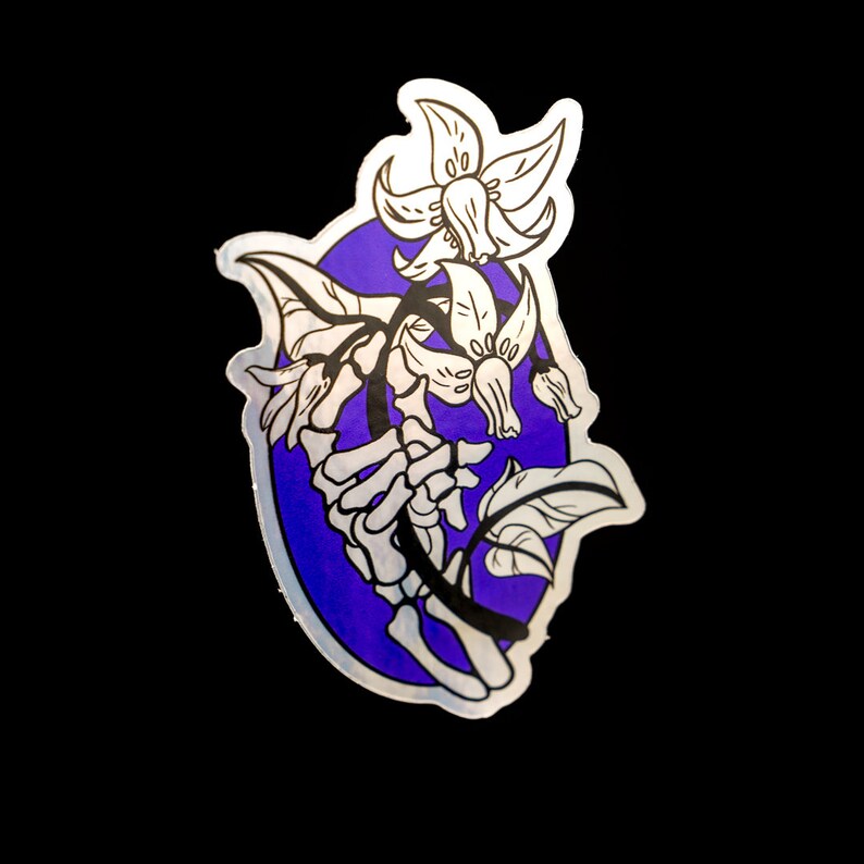 May include: A sticker featuring a white skeletal hand holding a bouquet of white flowers with purple accents. The flowers are stylised and have a whimsical feel. The background is a solid purple circle.
