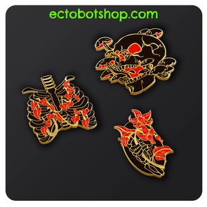 May include: Three enamel pins with a black and gold outline. The pins feature a skull with mushrooms, a rib cage, and a floral design, all with red accents. The website ectobotshop.com is visible in green text.