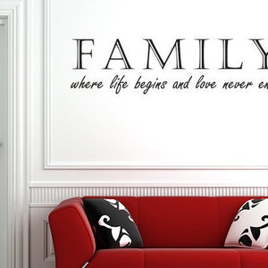 Könnte beinhalten: Eine weiße Wand mit den Worten "FAMILY where life begins and love never ends" in schwarzer Schrift. Im Vordergrund ein rotes Sofa mit weißen und schwarzen Kissen mit Mustern.