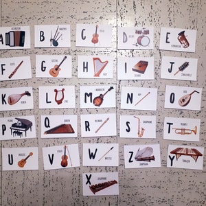 Puede incluir: Un conjunto de flashcards del alfabeto con ilustraciones de diferentes instrumentos musicales. Cada tarjeta tiene una letra del alfabeto y el nombre del instrumento, como "A Acorde&oacute;n" y "B Gaita".