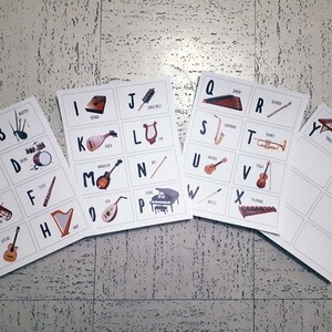 Puede incluir: Un conjunto de tarjetas de memoria alfab&eacute;ticas con instrumentos musicales. Cada tarjeta tiene una letra del alfabeto y un instrumento correspondiente, como un ukelele para la letra U y una trompeta para la letra T.