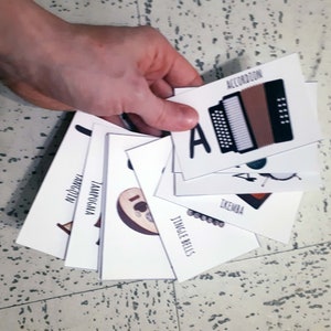 Puede incluir: Un conjunto de tarjetas de memoria con ilustraciones de diferentes instrumentos musicales, incluyendo un acorde&oacute;n, un pandero, un xil&oacute;fono, una campanilla, un timbal y un djembe.