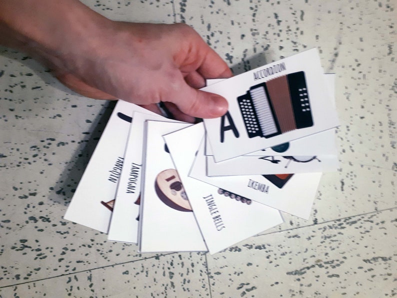Puede incluir: Un conjunto de tarjetas de memoria con ilustraciones de diferentes instrumentos musicales, incluyendo un acorde&oacute;n, un pandero, un xil&oacute;fono, una campanilla, un timbal y un djembe.