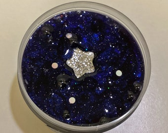 Rain at Midnight - a black clear slime with a blue hue. Glitter, sequins and droplet beads throughout. Comes with a silver star charm.