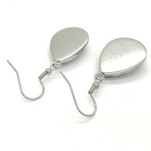 May include: A pair of silver teardrop-shaped earrings with a silver hook closure.