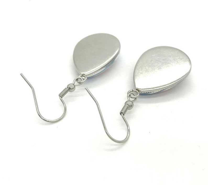May include: A pair of silver teardrop-shaped earrings with a silver hook closure.