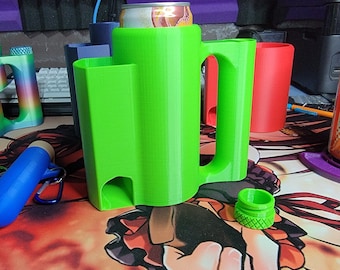 May include: A bright lime green 3D-printed beverage holder with a large handle and a cylindrical centre designed to hold a standard aluminium can. The holder features a secondary side compartment and a small circular opening at the base.