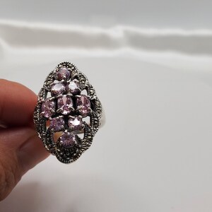 May include: A silver ring with a delicate design featuring a cluster of pink gemstones and a marcasite setting.