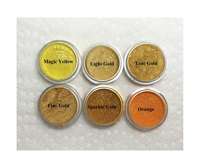 Puede incluir: Seis recipientes circulares de pigmento en polvo dispuestos en dos filas. Los colores est&aacute;n etiquetados como Magic Yellow, Light Gold, True Gold, Fine Gold, Sparkle Gold y Orange. Cada recipiente presenta un acabado met&aacute;lico o vibrante.