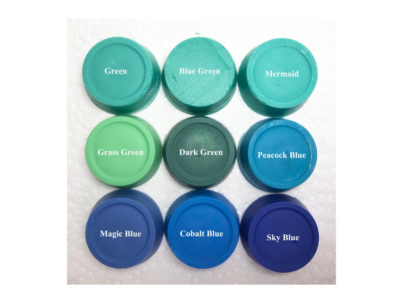 Puede incluir: Nueve recipientes circulares de cera o pigmento de colores dispuestos en una cuadr&iacute;cula de tres por tres. Las etiquetas dicen Green, Blue Green, Mermaid, Grass Green, Dark Green, Peacock Blue, Magic Blue, Cobalt Blue y Sky Blue en blanco.