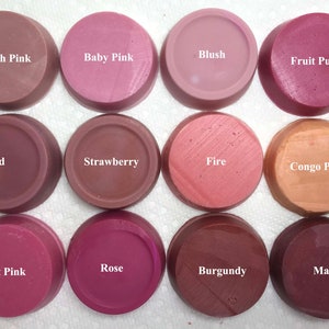 Puede incluir: Doce ceras arom&aacute;ticas circulares dispuestas en una cuadr&iacute;cula, cada una etiquetada con su nombre de color: Peach Pink, Baby Pink, Blush, Fruit Punch, Red, Strawberry, Fire, Congo Pink, Hot Pink, Rose, Burgundy y Mauve. Cada pieza es lisa y plana.