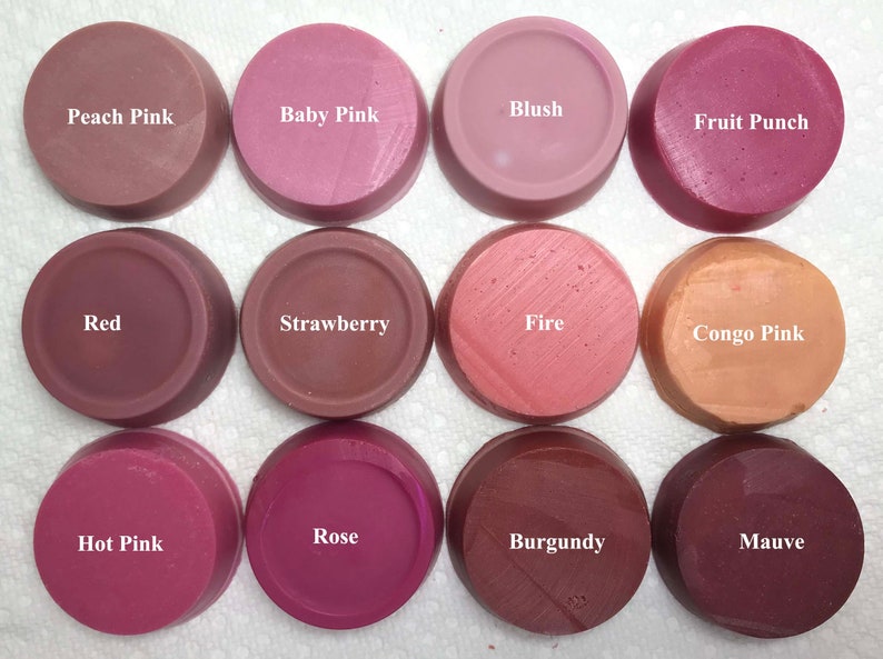 Puede incluir: Doce ceras arom&aacute;ticas circulares dispuestas en una cuadr&iacute;cula, cada una etiquetada con su nombre de color: Peach Pink, Baby Pink, Blush, Fruit Punch, Red, Strawberry, Fire, Congo Pink, Hot Pink, Rose, Burgundy y Mauve. Cada pieza es lisa y plana.