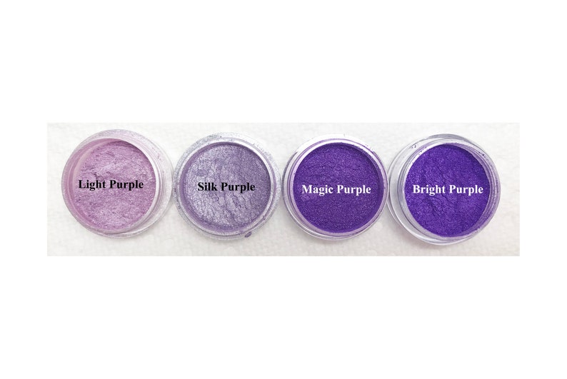 Puede incluir: Cuatro recipientes circulares transparentes llenos de polvo de mica morado en varios tonos. Las etiquetas dicen Light Purple, Silk Purple, Magic Purple y Bright Purple. Cada recipiente contiene un pigmento fino y brillante con acabado met&aacute;lico.
