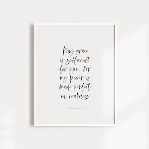 May include: A white framed print with a black and white inspirational quote: "My grace is sufficient for you, for my power is made perfect in weakness." The quote is from 2 Corinthians 12:9.