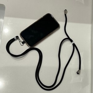 May include: A black phone strap with silver accents. The strap is made of a thick, durable material and has a simple design. The strap is attached to a phone case, which is not visible in the image.