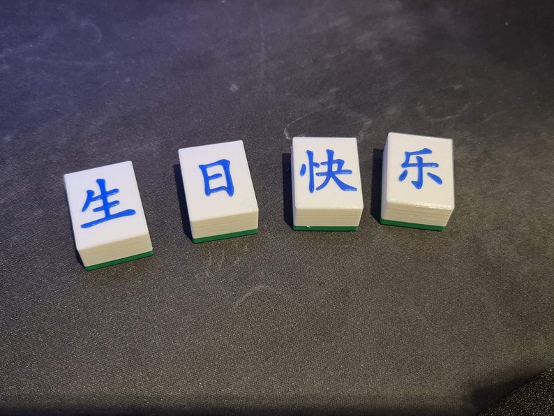 May include: Four white tiles with blue Chinese characters on them. The characters read "生 日 快 乐" which translates to "Happy Birthday".