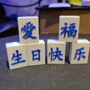 May include: White tiles with blue Chinese characters that read "Love Birthday Happy Year"