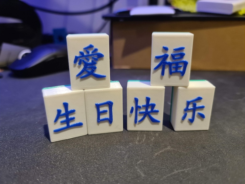 May include: White tiles with blue Chinese characters that read "Love Birthday Happy Year"