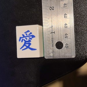 May include: A white tile with blue Chinese characters that read "愛" (love).