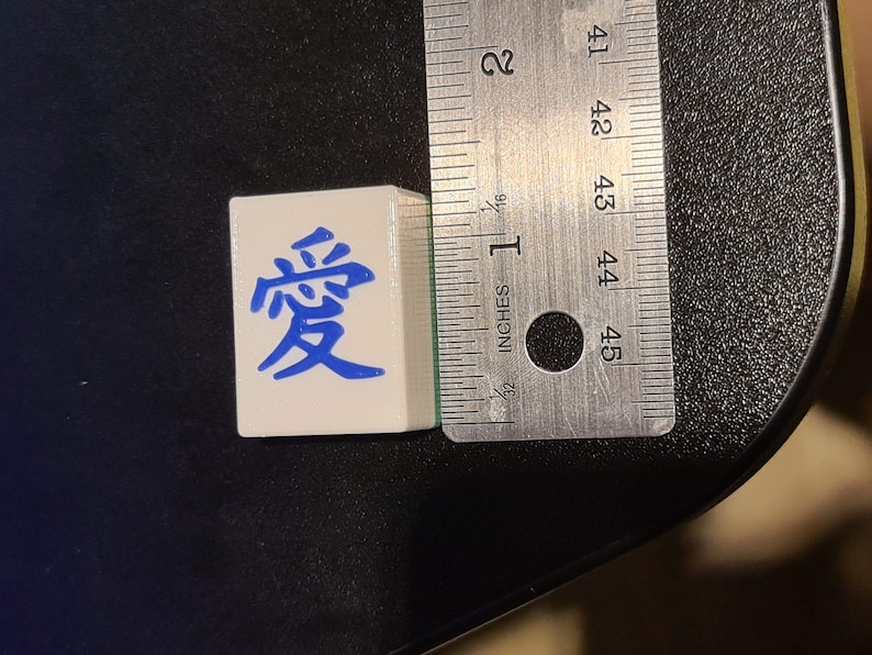 May include: A white tile with blue Chinese characters that read "愛" (love).