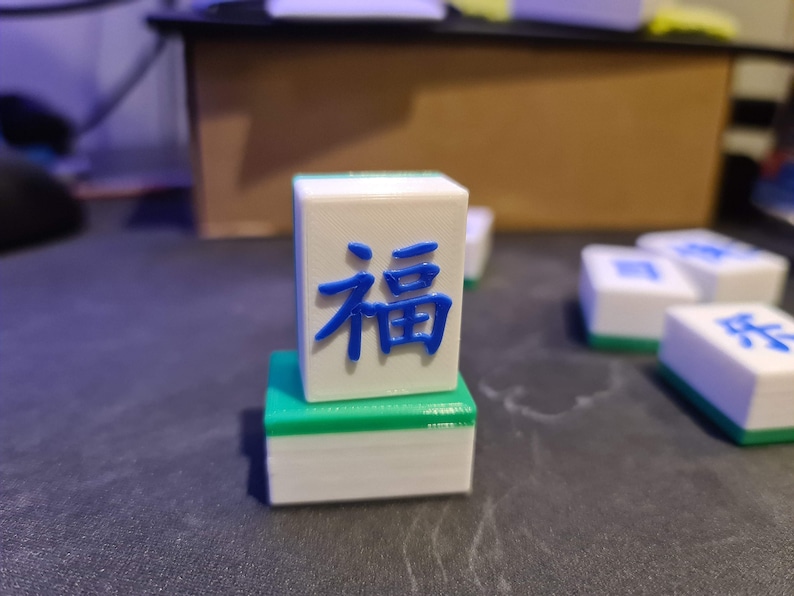 May include: A white and green mahjong tile with the Chinese character "福" (f&uacute;) meaning "fortune" or "good luck" in blue.
