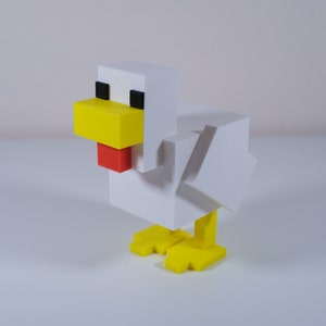 May include: A white, block-shaped chicken figurine with yellow beak, red wattle, and yellow feet. The figurine is made of plastic and has a pixelated design.