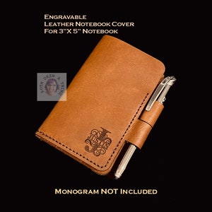 May include: A brown leather notebook cover for a 3" x 5" notebook. The cover has a pen holder and is engraved with a monogram. "MONOGRAM NOT INCLUDED" is written below the cover.
