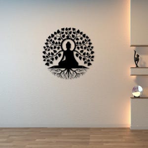 Puede incluir: Arte mural de metal negro que representa a un Buda meditando bajo un &aacute;rbol con ra&iacute;ces. La obra de arte circular presenta al Buda en el centro, rodeado de hojas y ra&iacute;ces. La pared es blanca y el suelo es de madera.