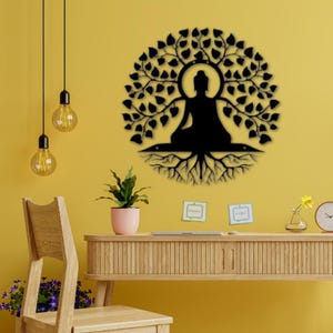 Puede incluir: Arte de pared de metal negro que representa a un Buda meditando bajo un &aacute;rbol. La imagen tambi&eacute;n muestra un escritorio de madera, una silla e iluminaci&oacute;n decorativa, todo sobre una pared amarilla.