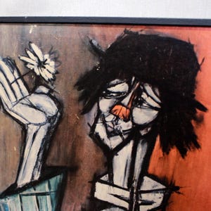 Op de afbeelding: Abstract schilderij in een zwarte lijst. Het kunstwerk toont een gestileerde figuur met een zwarte hoed en een oranje neus. Een witte hand houdt een madeliefje vast. De achtergrond is een mix van bruin en rood.