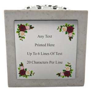 May include: A square, speckled, light gray memorial urn with a decorative silver trim. The front features a white panel with text: "Any Text Printed Here, Up To 6 Lines Of Text, 20 Characters Per Line." Floral corner accents.