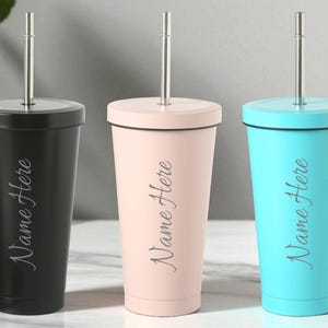 May include: Three insulated tumblers in black, pink, and turquoise, each with a silver straw and lid. The text "Name Here" is printed on the side of each tumbler. The tumblers are designed for cold drinks.