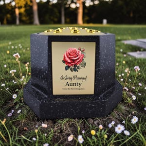 May include: Black memorial urn with a gold-colored top and a decorative plaque. The plaque features a red rose illustration and the text "In Loving Memory of Aunty, Gone But Never Forgotten."