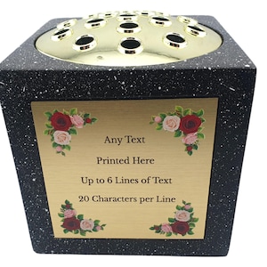 May include: Black speckled floral arrangement vase with a gold-colored top featuring multiple holes. A gold plaque on the front has text that reads "Any Text Printed Here Up to 6 Lines of Text 20 Characters per Line" with floral accents.